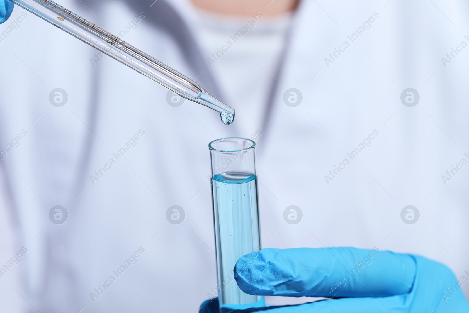 Photo of Scientist dripping liquid from pipette into test tube, selective focus