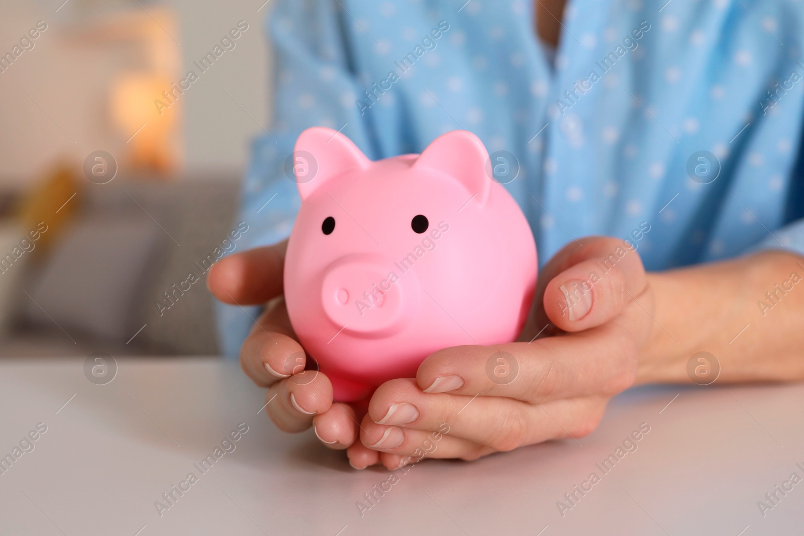 Photo of Woman with pink piggy bank at white table, closeup