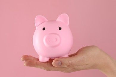 Photo of Woman with piggy bank on pink background, closeup