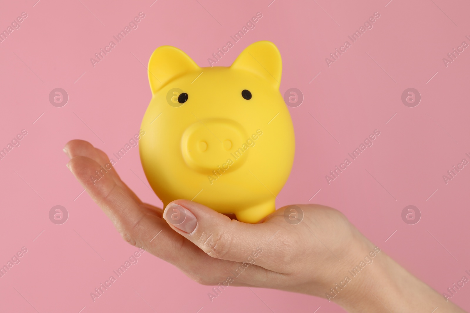 Photo of Woman with yellow piggy bank on pink background, closeup