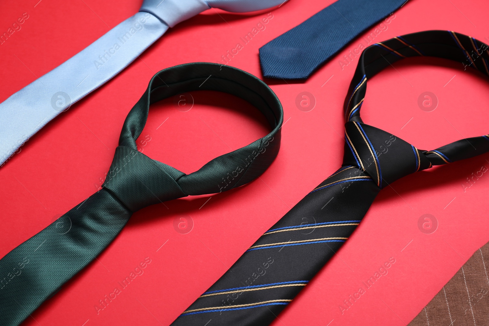 Photo of Many different neckties on red background, closeup