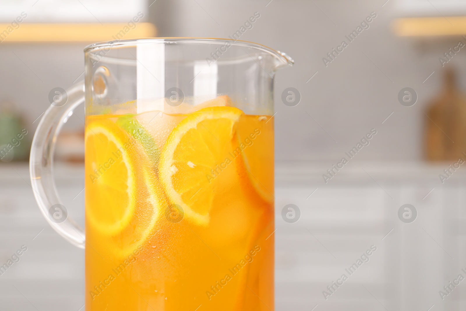 Photo of Freshly made lemonade in jug in kitchen, space for text