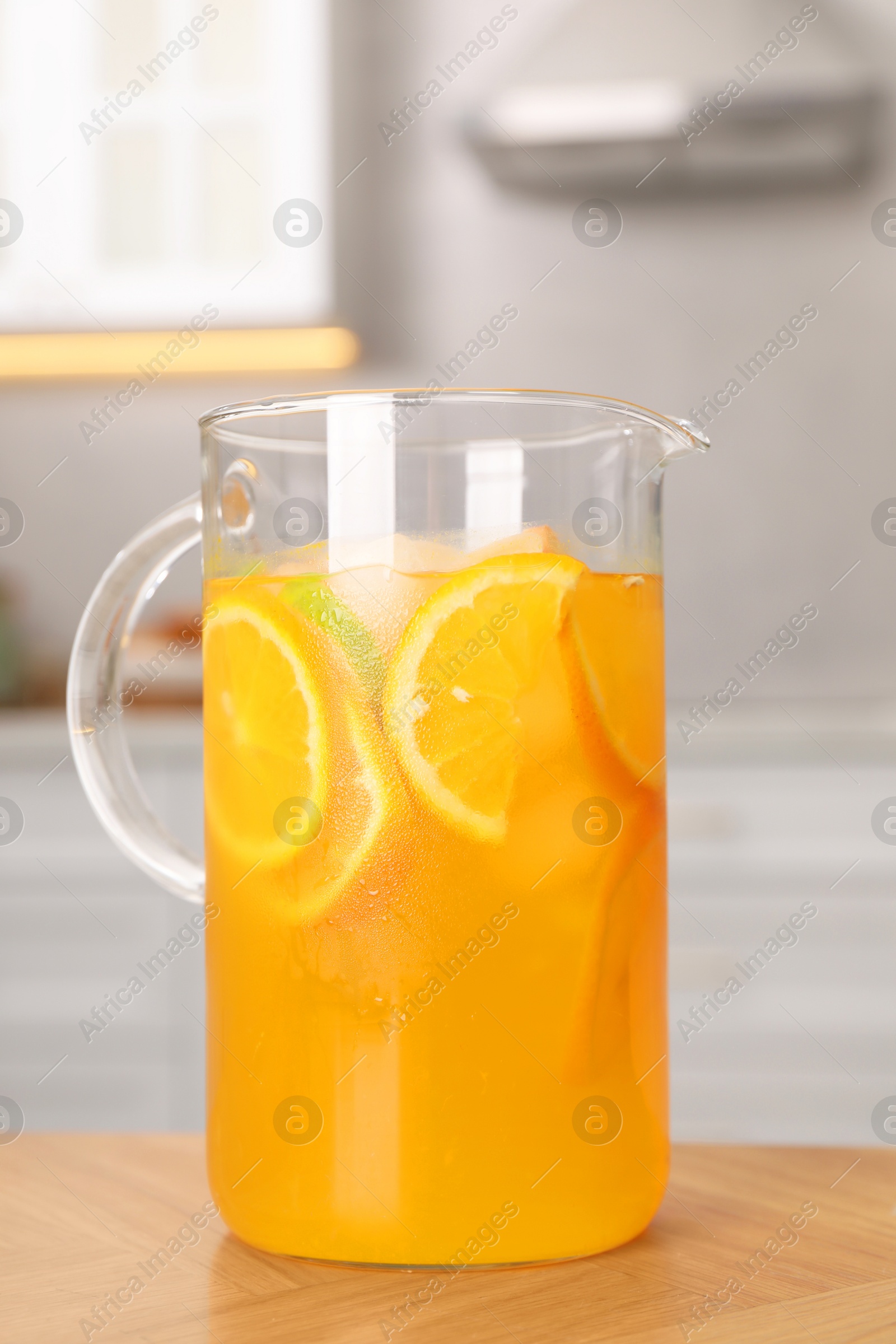 Photo of Freshly made lemonade in jug on wooden table in kitchen