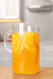 Freshly made lemonade in jug on wooden table in kitchen