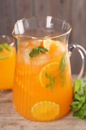 Photo of Freshly made lemonade in jug and mint on wooden table