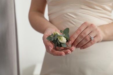 Photo of Bride holding boutonniere for her groom indoors, closeup