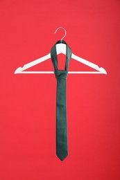 Photo of Hanger with teal tie on red background
