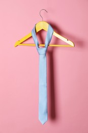 Hanger with light blue tie on pink background