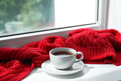 Red knitted scarf, hat, tea on windowsill
