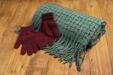 Photo of Soft green scarf and gloves on wooden table