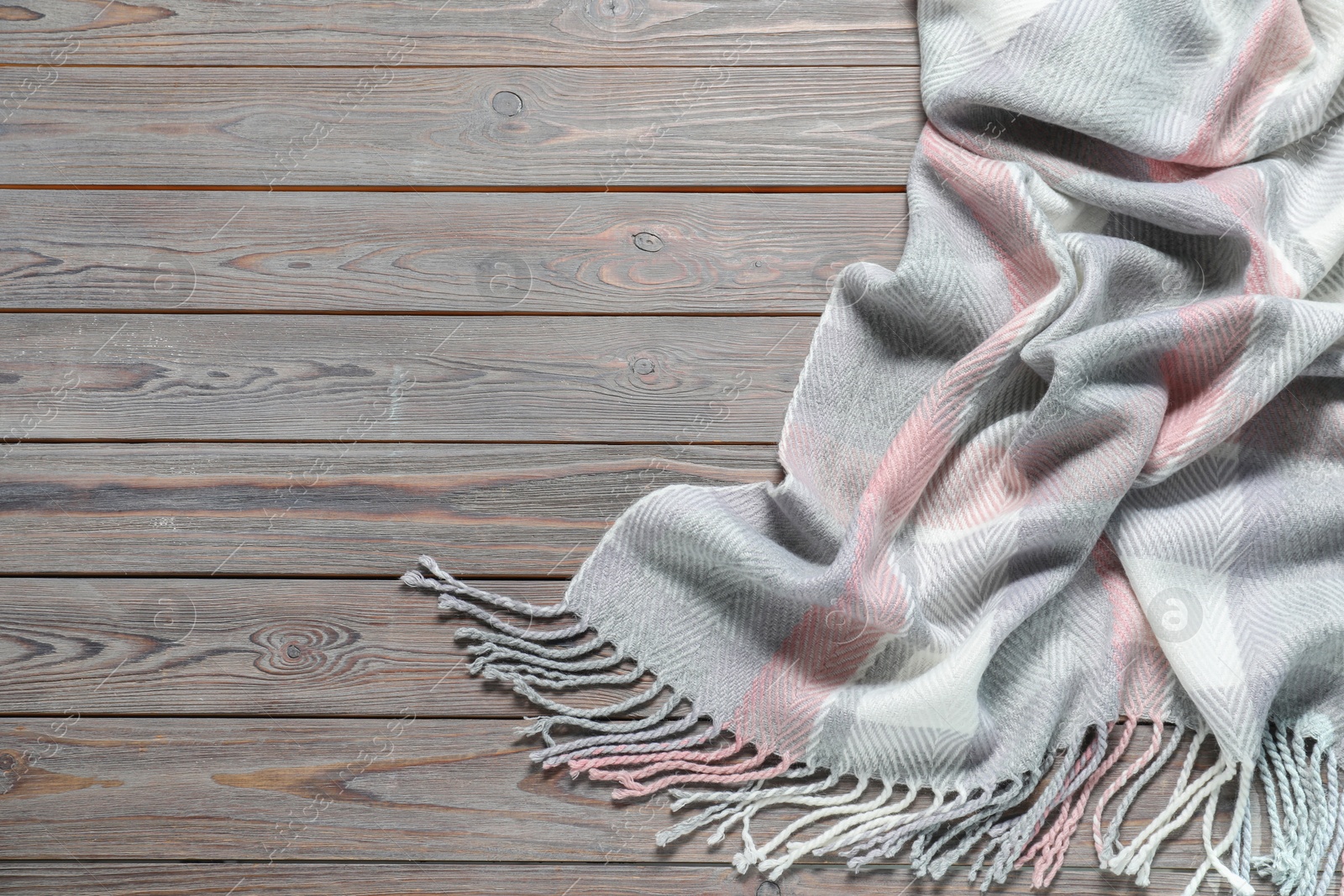 Photo of Soft checkered scarf on wooden table, top view. Space for text