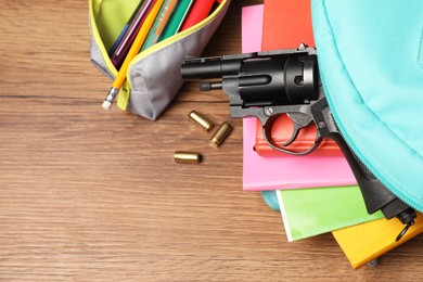 Photo of Gun, bullets and school stationery on wooden table, flat lay. Space for text