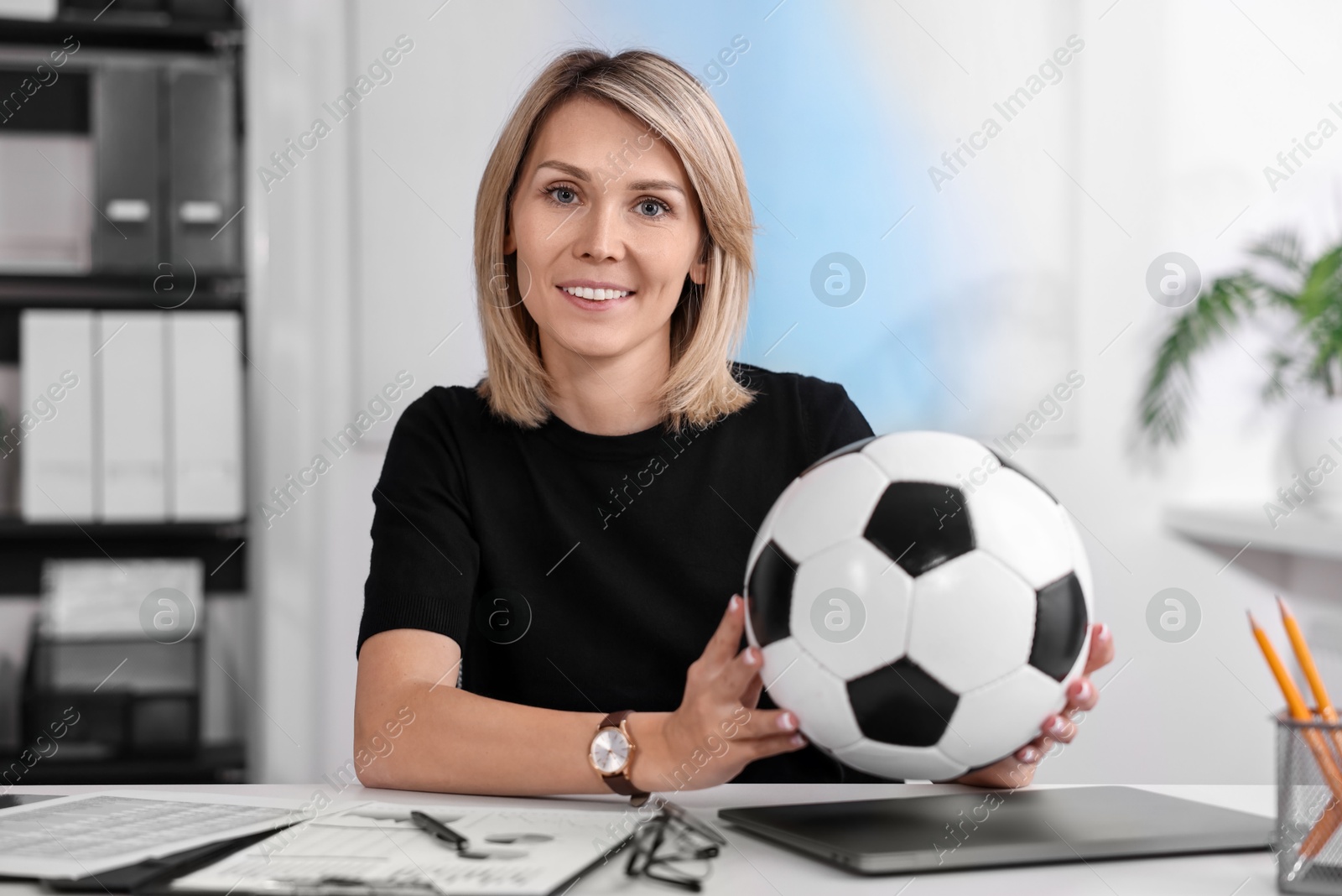 Photo of Smiling woman with soccer ball at table in office