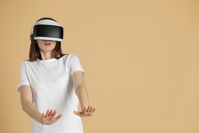 Woman using virtual reality headset on beige background, space for text