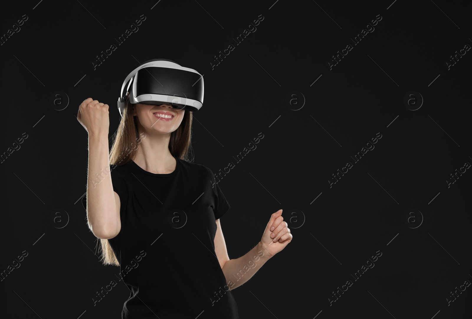 Photo of Smiling woman using virtual reality headset on black background, space for text