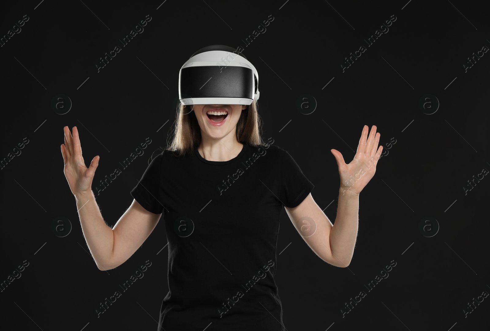 Photo of Surprised woman using virtual reality headset on black background