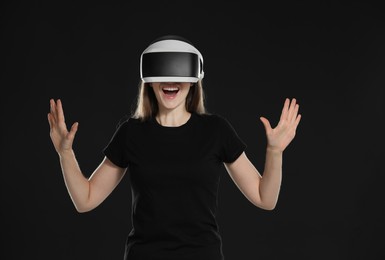 Photo of Surprised woman using virtual reality headset on black background