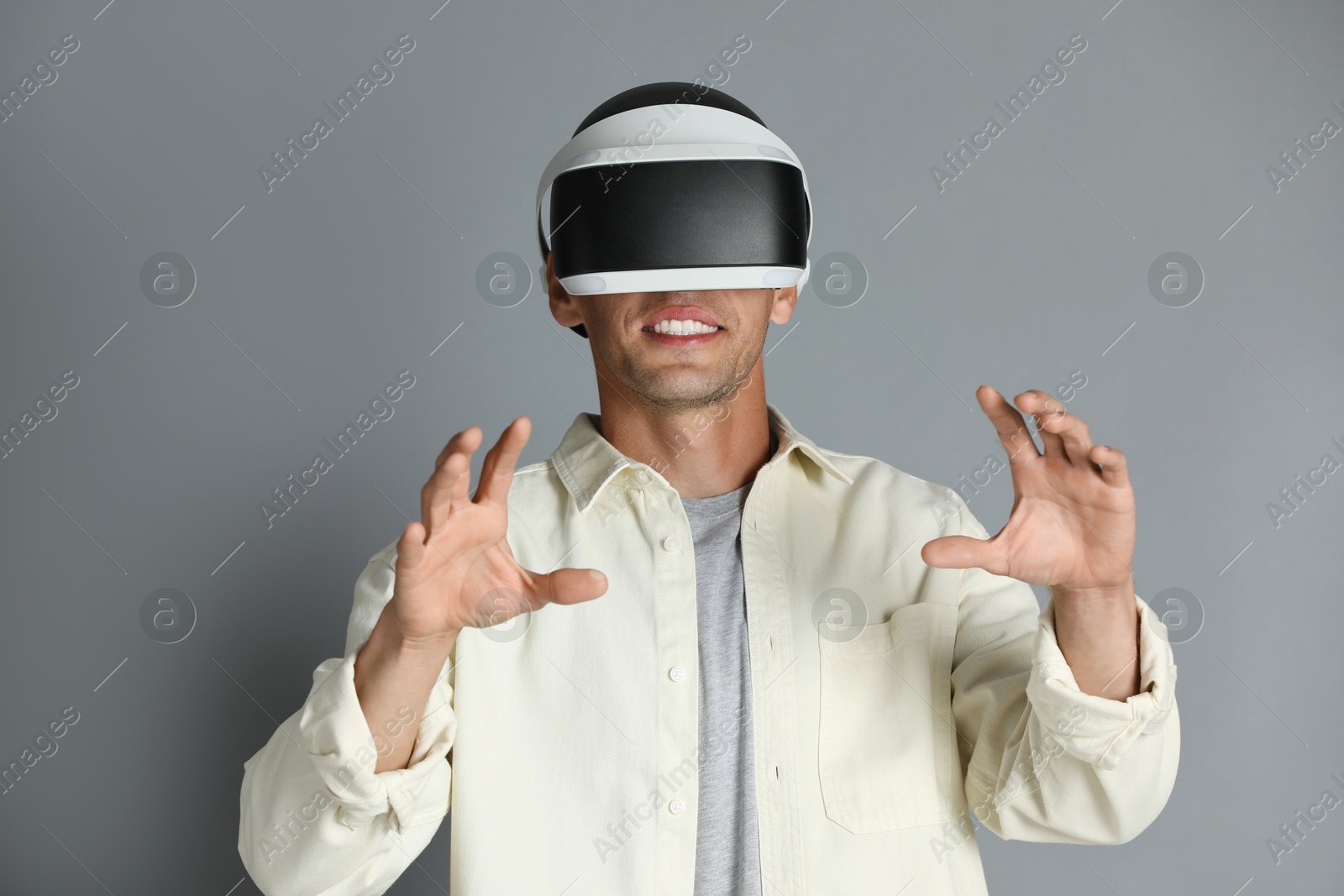 Photo of Smiling man using virtual reality headset on gray background