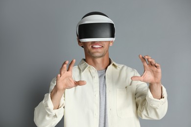 Photo of Smiling man using virtual reality headset on gray background