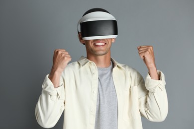 Smiling man using virtual reality headset on gray background