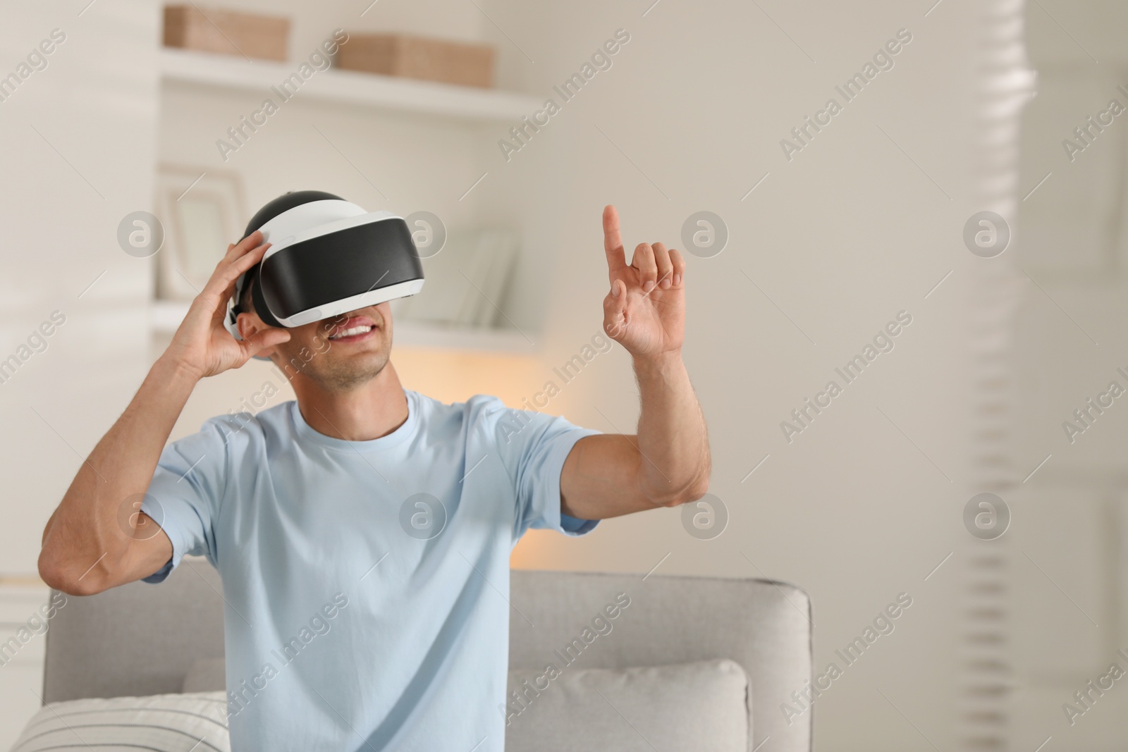 Photo of Smiling man using virtual reality headset at home