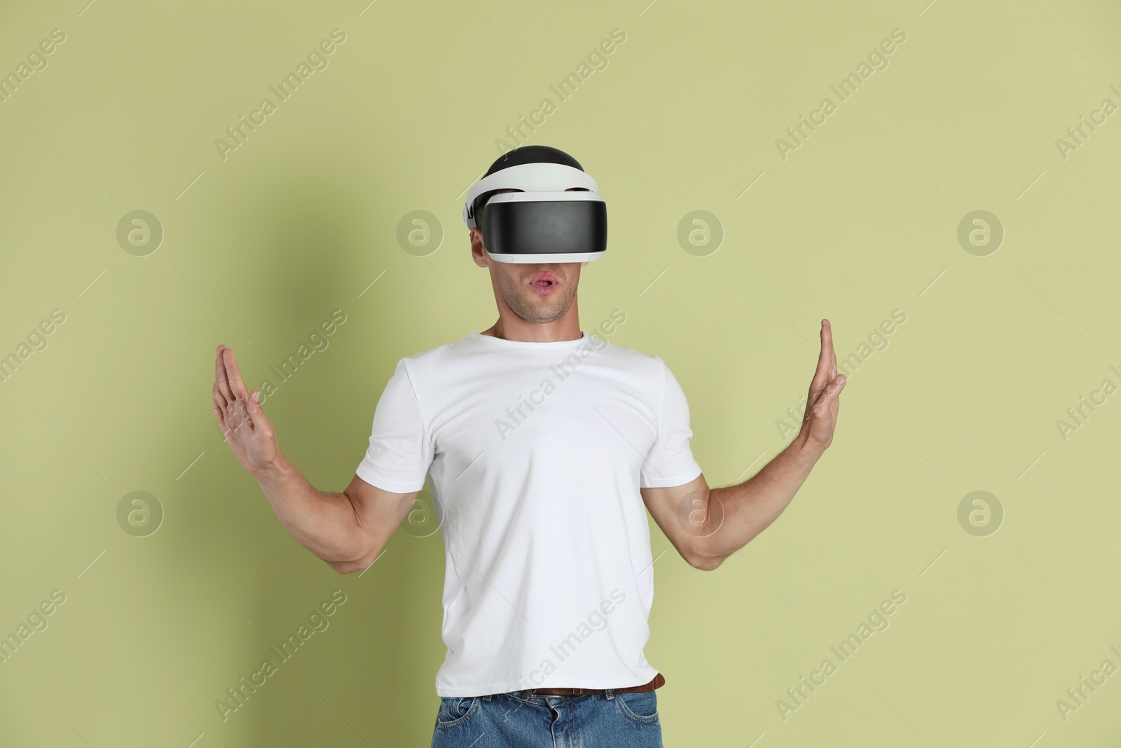 Photo of Surprised man using virtual reality headset on light green background