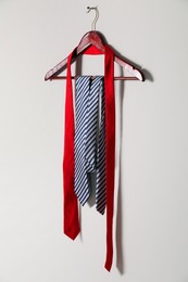 Hanger with different stylish neckties on light wall