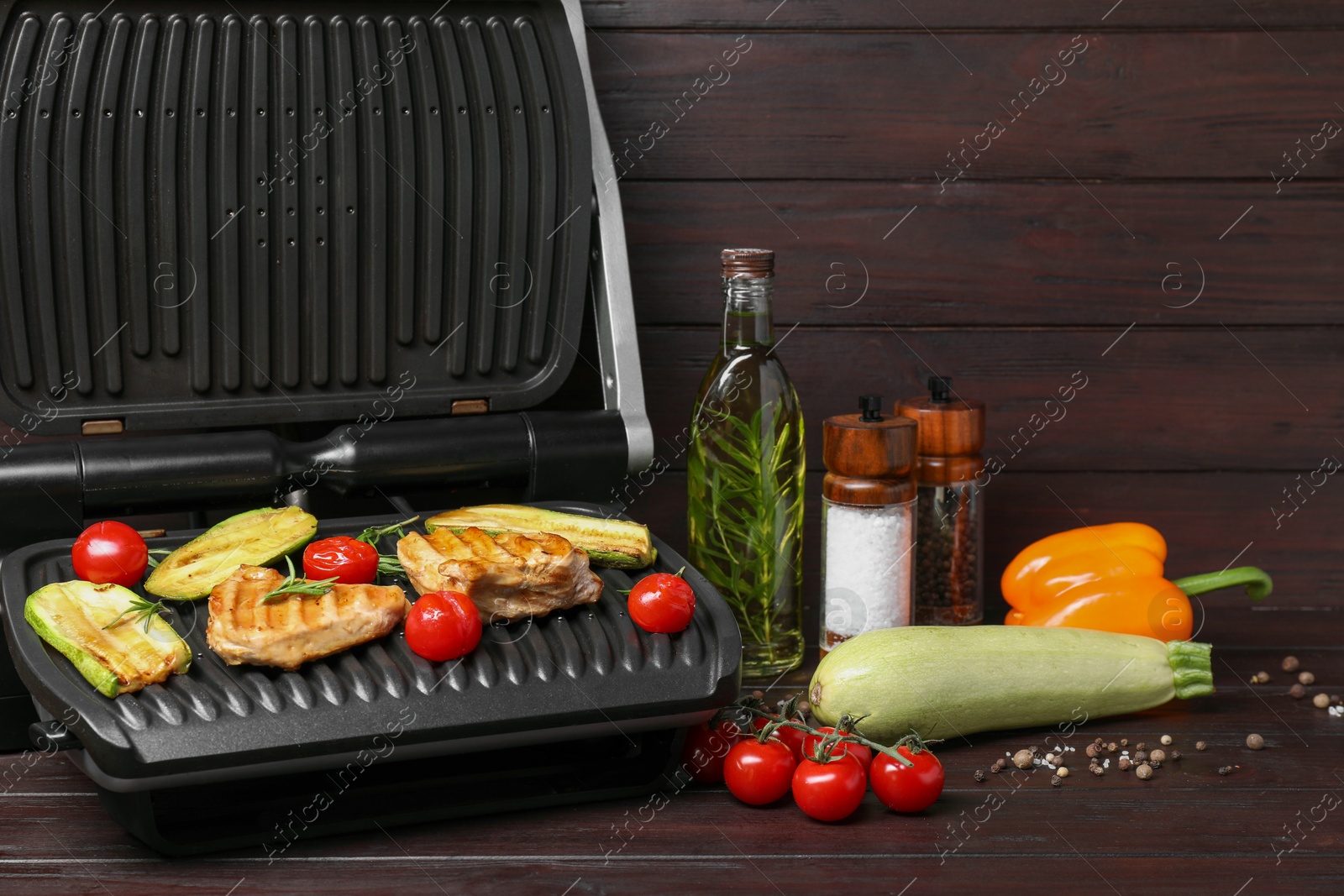 Photo of Electric grill with different products on wooden table