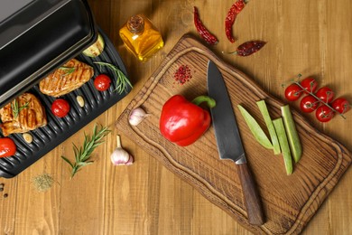 Flat lay composition with electric grill and different products on wooden table