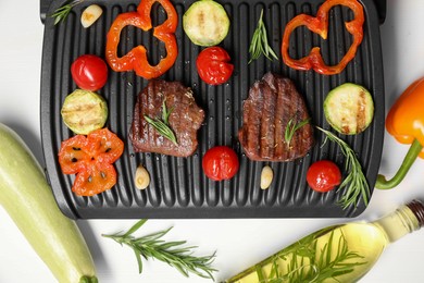 Electric grill with tasty meat, spices and vegetables on white table, flat lay