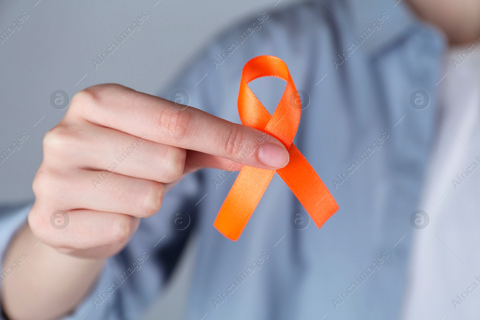 Photo of Woman with orange awareness ribbon on grey background, closeup