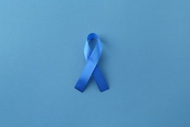 Photo of Blue awareness ribbon on color background, top view