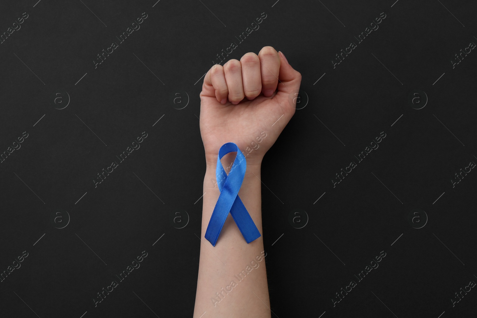 Photo of Woman with blue awareness ribbon on black background, top view