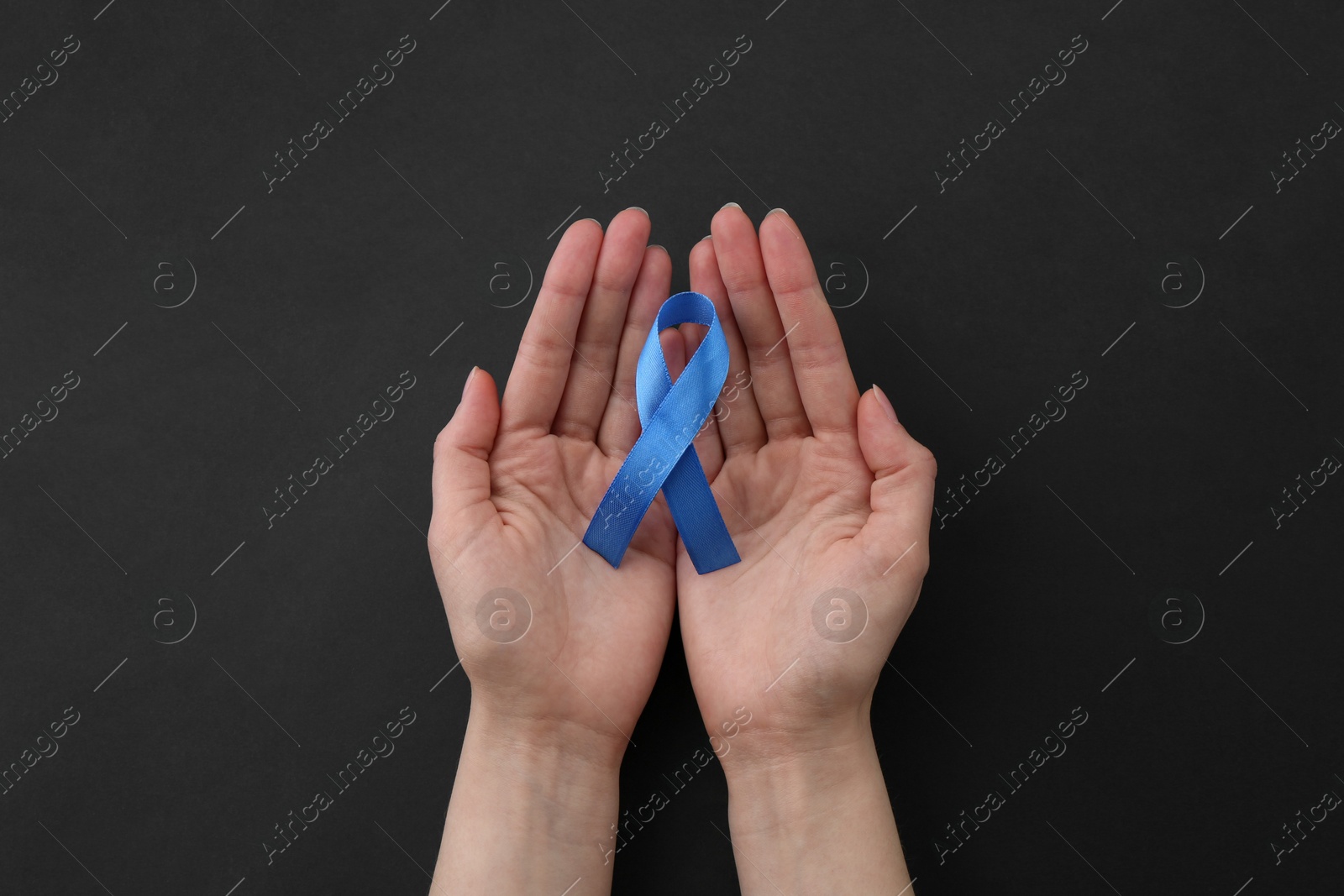 Photo of Woman with blue awareness ribbon on black background, top view