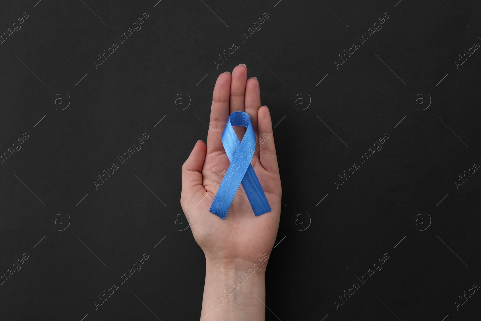 Photo of Woman with blue awareness ribbon on black background, top view