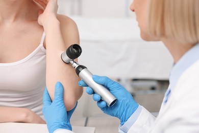 Photo of Dermatologist with dermatoscope examining patient in clinic, closeup