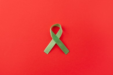 Light green awareness ribbon on red background, top view