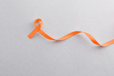 Photo of Orange awareness ribbon on gray background, top view. Space for text