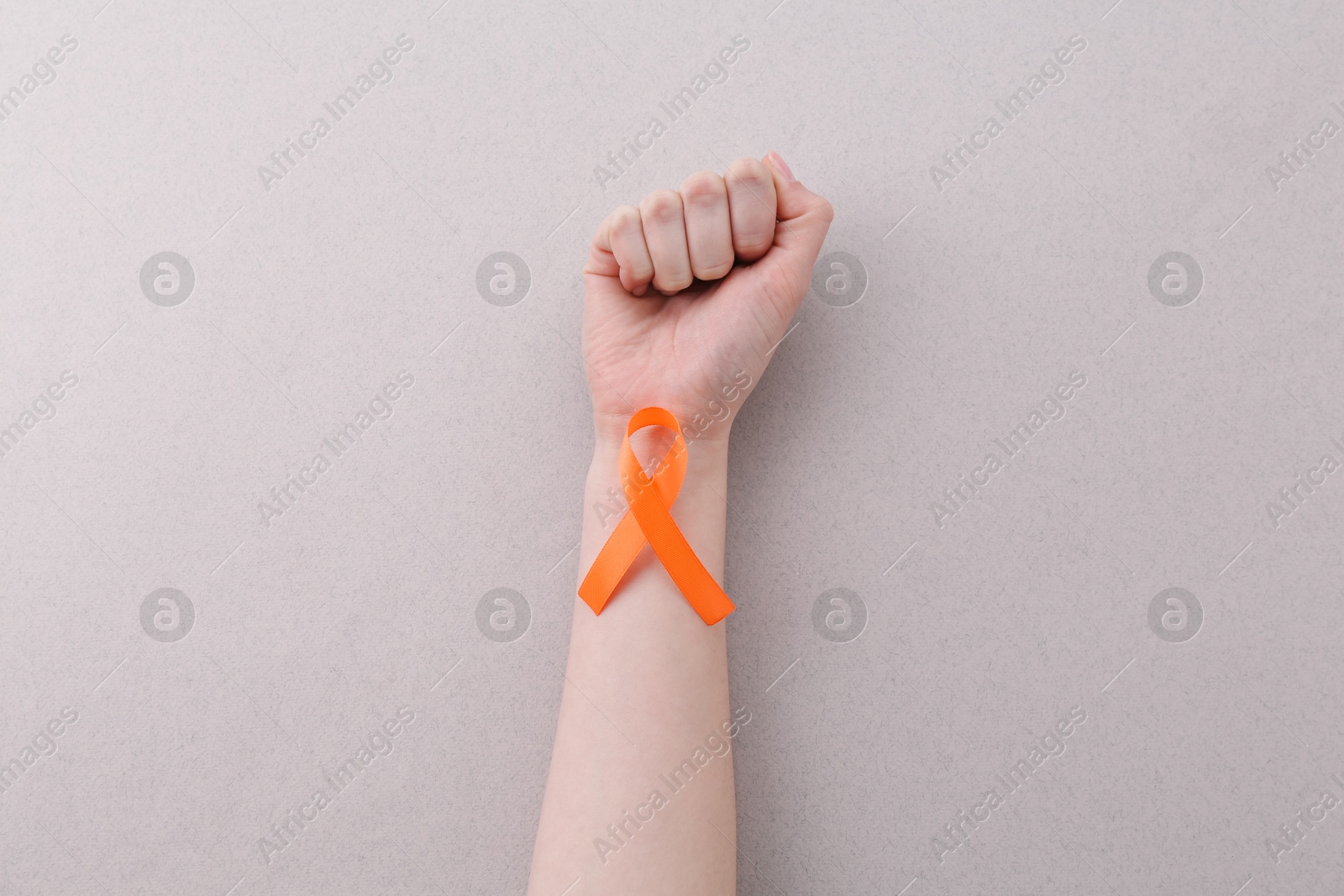 Photo of Woman with orange awareness ribbon on gray background, top view