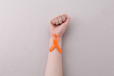 Woman with orange awareness ribbon on gray background, top view