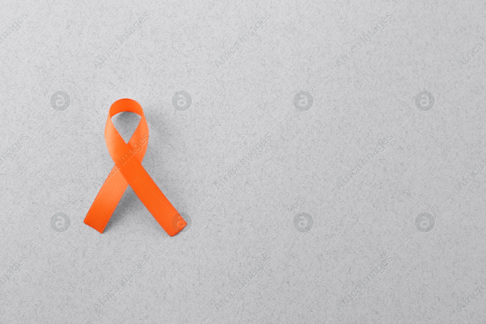 Photo of Orange awareness ribbon on gray background, top view. Space for text