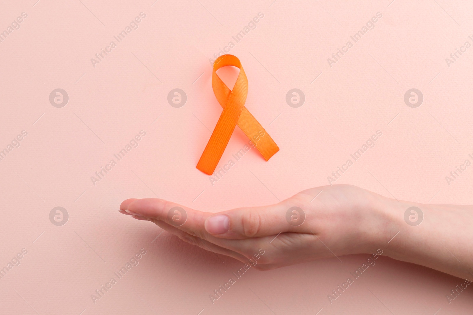 Photo of Woman with orange awareness ribbon on beige background, top view