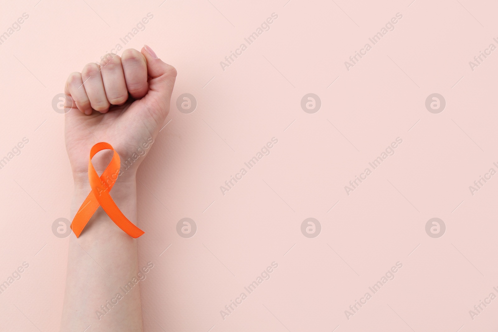 Photo of Woman with orange awareness ribbon on beige background, top view. Space for text