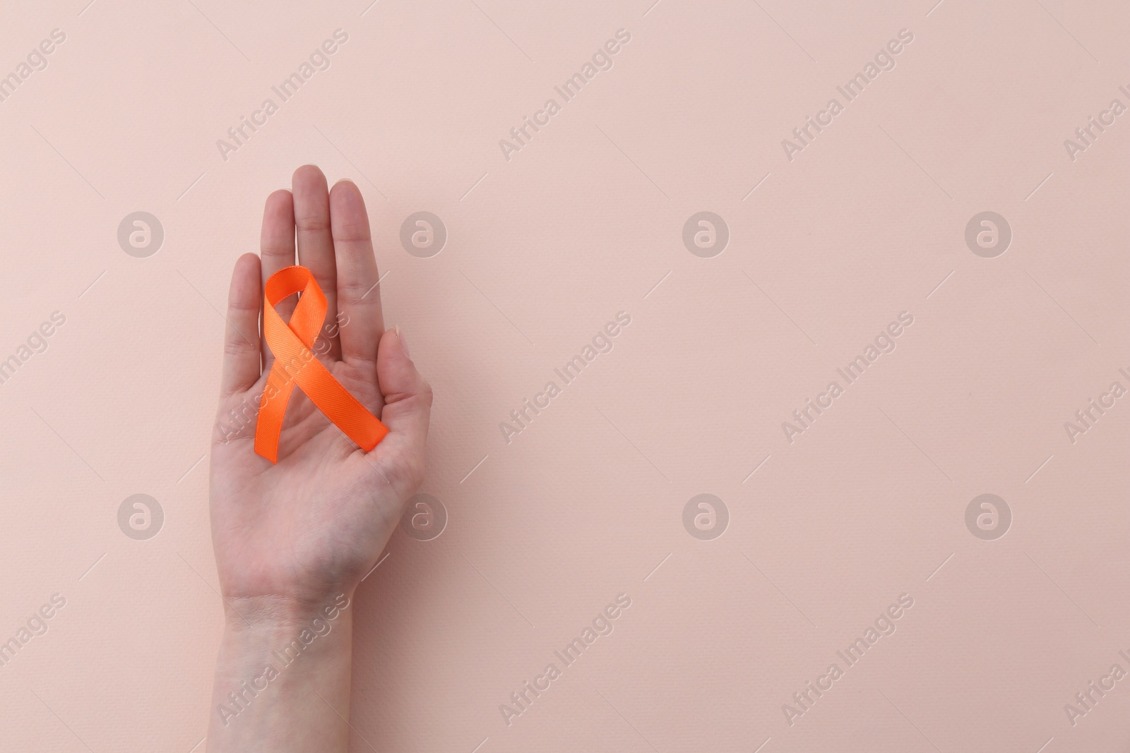Photo of Woman with orange awareness ribbon on beige background, top view. Space for text