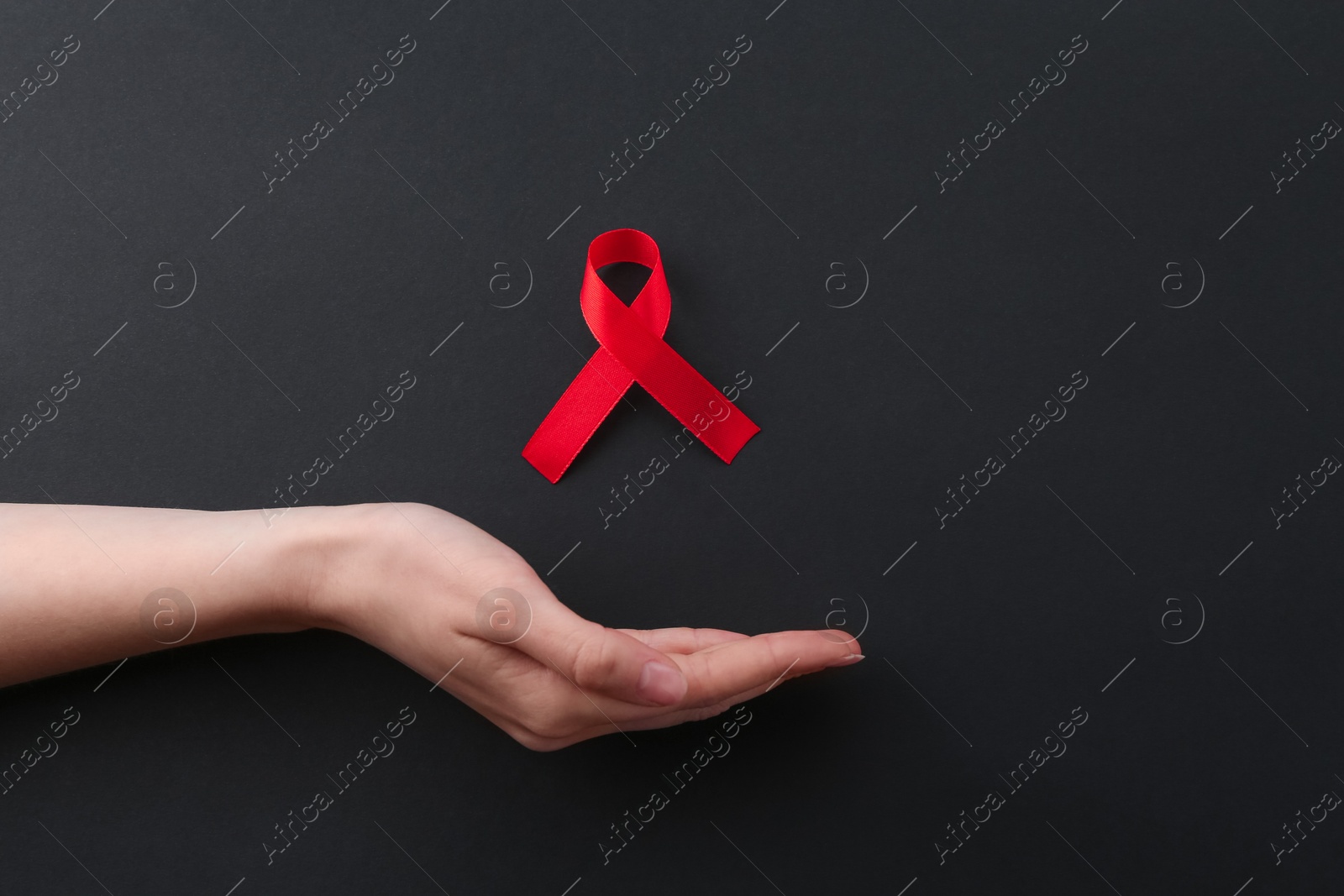 Photo of Woman with red awareness ribbon on black background, flat lay