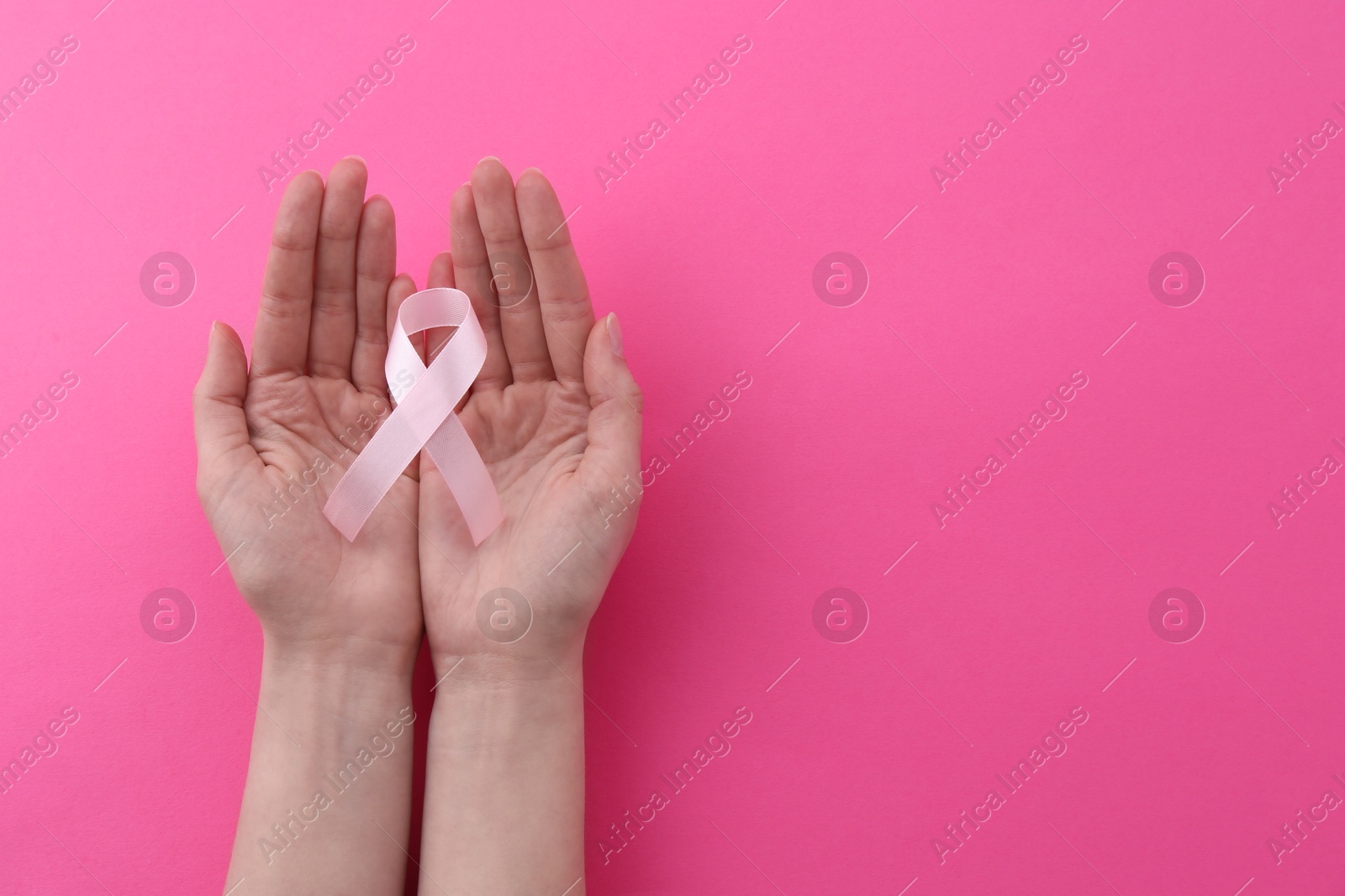 Photo of Woman with awareness ribbon on pink background, top view. Space for text