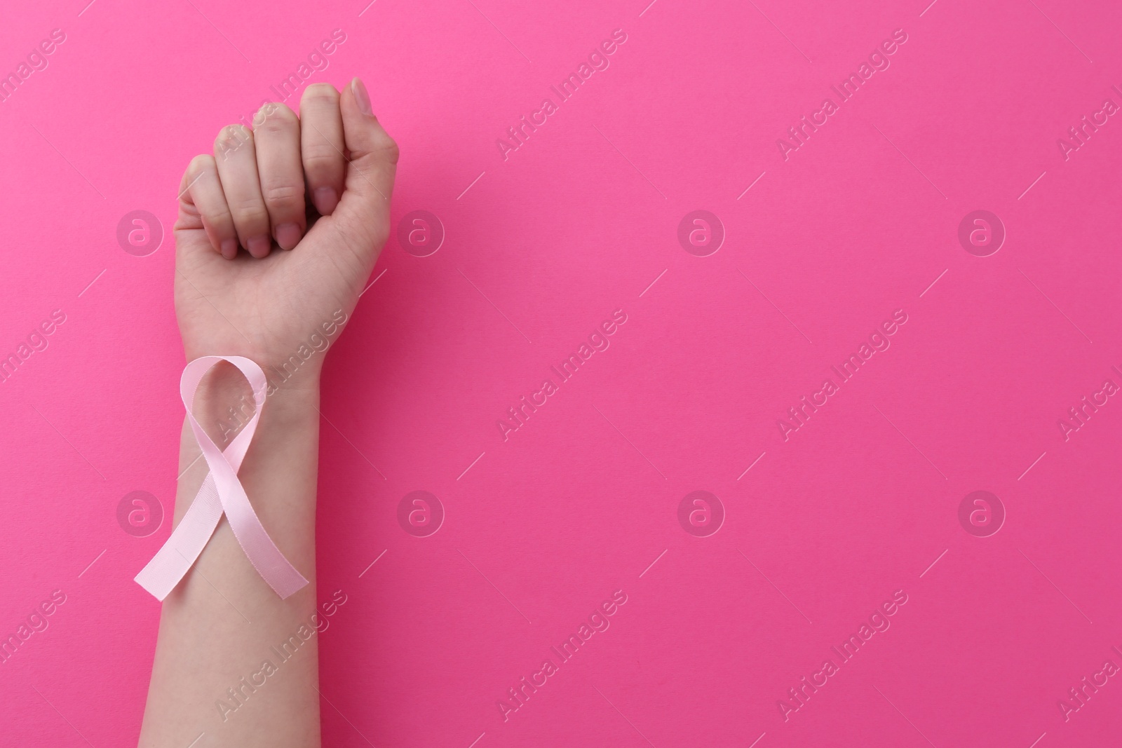 Photo of Woman with awareness ribbon on pink background, top view. Space for text