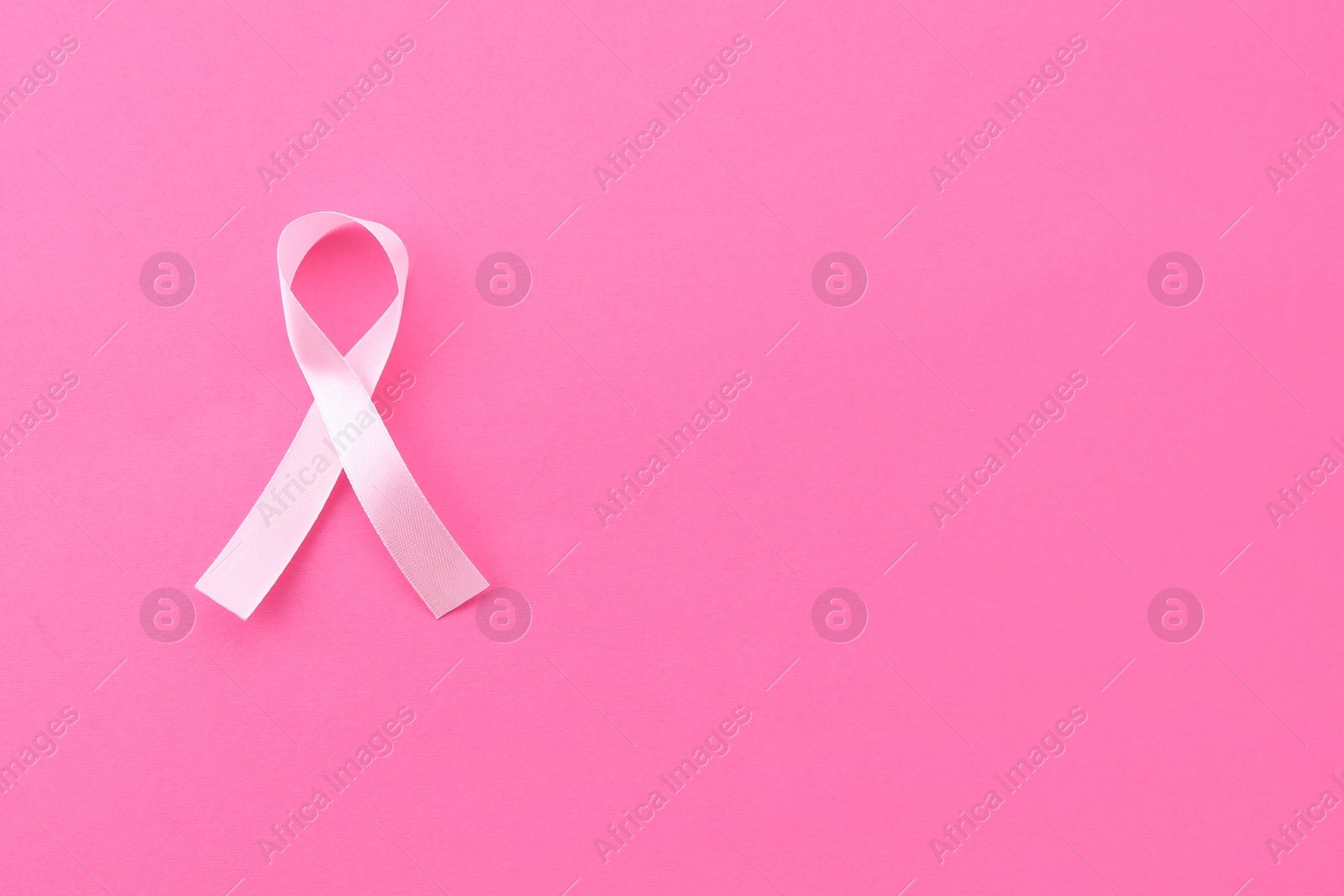 Photo of Awareness ribbon on pink background, top view. Space for text