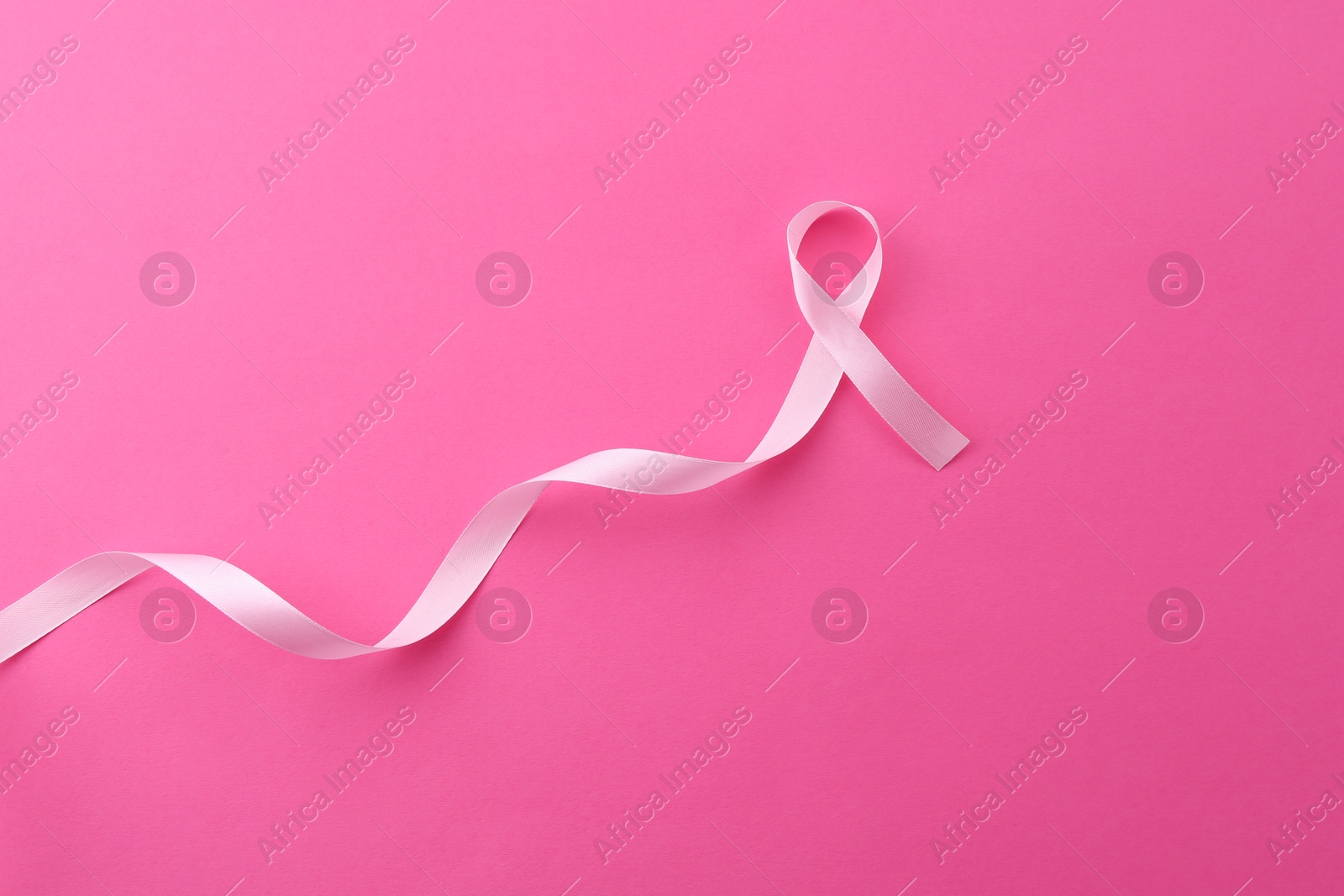 Photo of Awareness ribbon on pink background, top view. Space for text