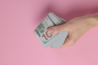 Photo of Money exchange. Woman holding dollar banknotes on pink background, top view